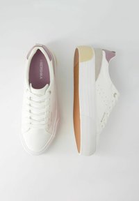 Bílé tenisky s texturovanou gumovou podrážkou, růžovými doplňky na patě a jazyku, kulatou špičkou a šněrováním. Minimalistický styl.