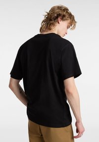 T-shirt in cotone nero con vestibilità rilassata, maniche corte e collo a giro. Cuciture visibili sui bordi. Design semplice senza pattern.