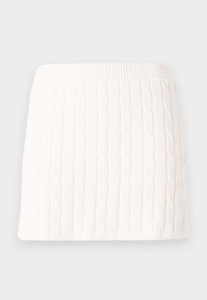 Mini-jupe blanche en maille avec motif torsadé et taille élastique sur fond uni.
