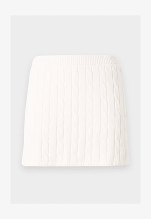 Mini-jupe blanche en maille avec motif torsadé et taille élastique sur fond uni.