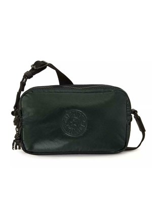Petit sac noir porté en bandoulière avec sangle réglable, logo circulaire embossé sur le devant, et petit porte-clés attaché à la fermeture éclair.