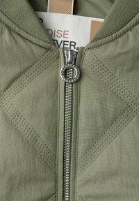 Lichtgroene jas met een centrale rits, geribbelde kraag en ruitvormige stiksels op de stof voor extra textuur.