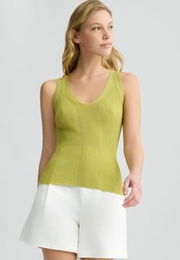 Canotte a coste verde lime con scollo a V e senza maniche, abbinata a pantaloni corti bianchi. Presenta un tessuto testurizzato e una silhouette aderente.