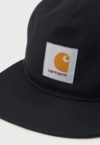 Czarna czapka Carhartt z wyszywaną prostokątną naszywką z stylizowanym pomarańczowym "C" i czerwonym napisem Carhartt z przodu.