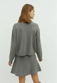 Grijze gebreide trui met een cropped ontwerp en lange mouwen, gecombineerd met een bijpassende uitlopende rok. Strakke textuur, casual stijl.