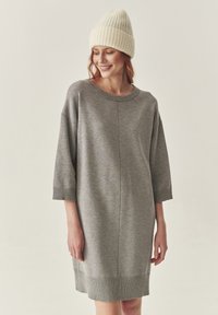 Szara sukienka z dresu o luźnym kroju, z prążkowanymi mankietami i do�łem. Miękka tekstura i okrągły dekolt, w połączeniu z jasnym dzianinowym beanie.