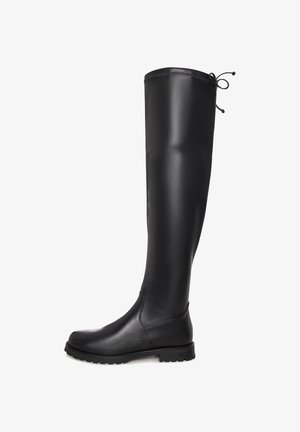 Stivale in pelle nera, fino al ginocchio, con punta arrotondata, suola bassa in gomma e cordoncino regolabile sul retro in alto.