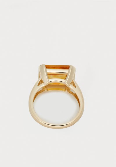 Bague en or ornée d'une pierre d'ambre rectangulaire avec un sertissage géométrique. Bande lisse avec des découpes sur les côtés.