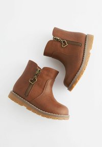 Brązowe ankle bootsy z sztucznej skóry z bocznym zamkiem błyskawicznym, zdobione serduszkowym uchwytem oraz teksturowaną podeszwą zapewniającą grip.