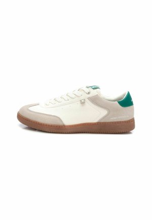 Zapatilla blanca y gris claro con un upper de gamuza texturizada y cuero liso. Presenta un detalle en el talón verde y una suela de goma marrón.