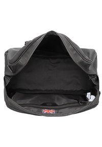 Mustat nahkakassi vetoketjukiinnityksellä, jossa on tilava sisustus ja pieni vetoketjullinen tasku. Mukana on tagi, jossa on brittilippu.