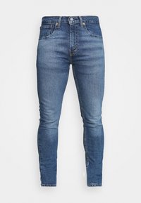 Vaqueros de mezclilla azul slim fit para hombre, con bolsillos frontales, pasadores para cinturón y cierre de botón sobre un fondo blanco.