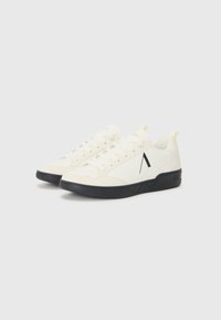 Zapatillas blancas con un diseño texturizado, suela de goma negra y un prominente logo negro con la 'A'. Incluyen un collar acolchado y cordones en la parte frontal.