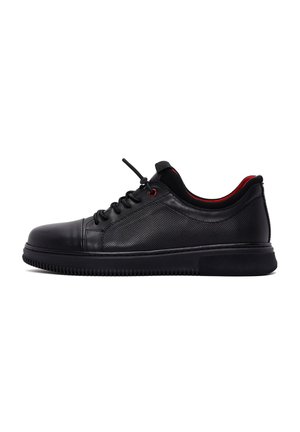 Black leather athletic shoe with a perforated design, red accents, lace-up closure, and a thick rubber sole. Textured surface for grip.