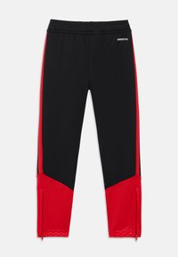 Calças desportivas pretas com painéis laterais vermelhos, punhos com fecho éclair e cintura elástica. Feitas de tecido elástico e respirável para maior conforto.