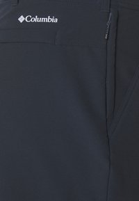 Marineblaue Columbia-Hose mit einem Reißverschlussfach und einer glatten, matten Stoffoberfläche mit dezentem Glanz. Einfaches Design mit verstärkten Nähten.