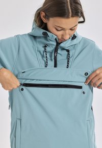 Pullover azzurro chiaro con cappuccio, zip frontale e dettagli neri. Presenta una tasca con zip sul davanti e un tessuto testurizzato.