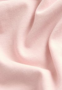 Helle rosa strukturierte Stoff mit einem feinen Rippenmuster, das weiche, glatte Fäden zeigt, die sanfte Falten und Drapierungen erzeugen.