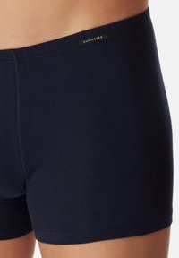 Boxer shorts in cotone blu navy con una texture liscia e una cintura elastica stretta con etichetta nera. Senza pattern visibili.