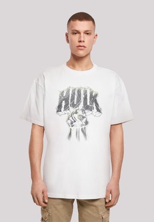 Hvit bomulls t-skjorte med et grafisk motiv av en knyttet neve og "HULK"-tekst i grått med grønne detaljer. Korte ermer og avslappet passform.