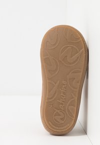 Bruine rubberen zool met een gemarmerd patroon, featuring cirkelvormige logo-ontwerpen en het cijfer "21" in reliëf. Iets transparant met een gladde afwerking.