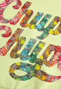 Jasnozielona bluza z kolorowymi wzorami lizaków w odważnym tekście. Miękki materiał o gładkiej teksturze i wyrazistych grafikach.