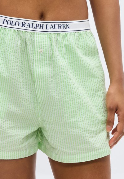 Μέση και άνω μέρος των ποδιών ενός ατόμου που φοράει ανοιχτοπράσινα και λευκά ριγέ εσώρουχα Polo Ralph Lauren με κουμπιά και ελαστική ζώνη μέσης.