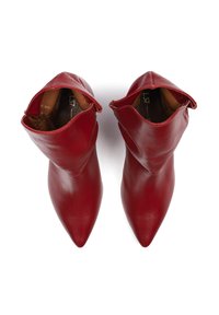Stivali alla caviglia in pelle rossa con punta appuntita e design a risvolto, caratterizzati da una texture liscia e una fodera interna marrone.