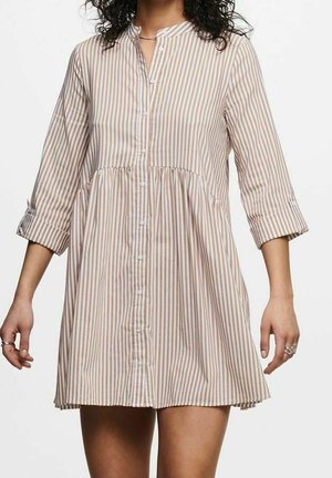 Sukienka koszulowa w paski w kolorach beżowym i jasnobrązowym. Posiada zapięcie na guziki z przodu, dekolt bez kołnierzyka oraz rękawy długości 3/4 z podwiniętymi mankietami.