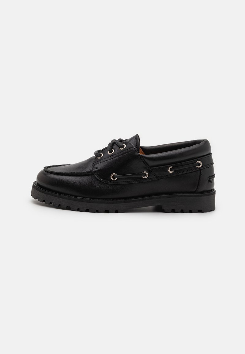 Black leather boat shoe with a rounded toe, lace-up front, decorative eyelets, and textured rubber sole. Plain design and smooth finish.