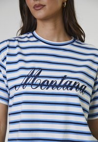 Camiseta de manga corta a rayas en blanco y diferentes tonalidades de azul. Cuenta con un bordado en navy que dice "Montana" en el pecho.