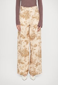 Pantaloni largi din țesătură bej, cu un model floral în nuanțe de maron. Croi înalt, cu buzunare laterale, terminați cu o textură netedă.