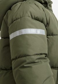 Manica di giacca imbottita verde oliva con una striscia riflettente orizzontale sulla parte superiore del braccio, dettagli cuciti visibili.