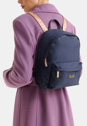 Zaino in nylon blu marina con forma arrotondata, cerniere dorate e una tasca frontale. Presenta una tracolla beige con motivo e un manico superiore per il trasporto.
