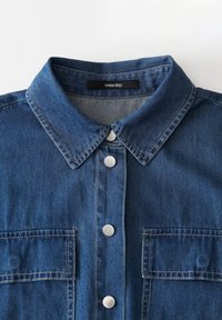 Camicia in denim blu con collo, bottoni a pressione argentati e due tasche anteriori. Presenta cuciture a contrasto e una texture fresca.