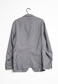 Grijs en wit gestreepte button-up shirt met een notch-kraag, lange mouwen, zijsplitten en een gladde katoentextuur, hangt aan een haak.