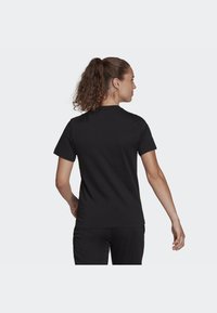 Tricou negru cu mâneci scurte, cu guler rotund, textură netedă și un design slim-fit, văzut din spate.