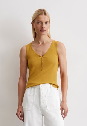 Mustard yellow ribbed tank top with a V-neckline and three buttons at the front, paired with high-waisted white jeans.