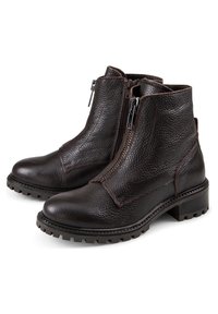 Bottines en cuir marron avec une finition texturée, zips sur les côtés et une semelle épaisse à motifs. Présente un petit talon et des détails de couture.