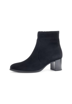 Botte de cheville en suède noir avec un bout arrondi, des coutures minimales et un talon épais pour la stabilité. Texture lisse, design élégant et polyvalent.