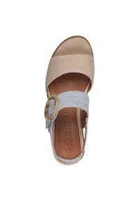 Sandale en suède beige clair et bleu avec une semelle intérieure en cuir tan, présentant un accent en métal doré circulaire et un talon plat.