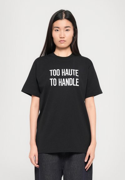 Black cotton t-shirt with short sleeves and a crew neck, featuring the text "TOO HAUTE TO HANDLE" in bold white lettering.