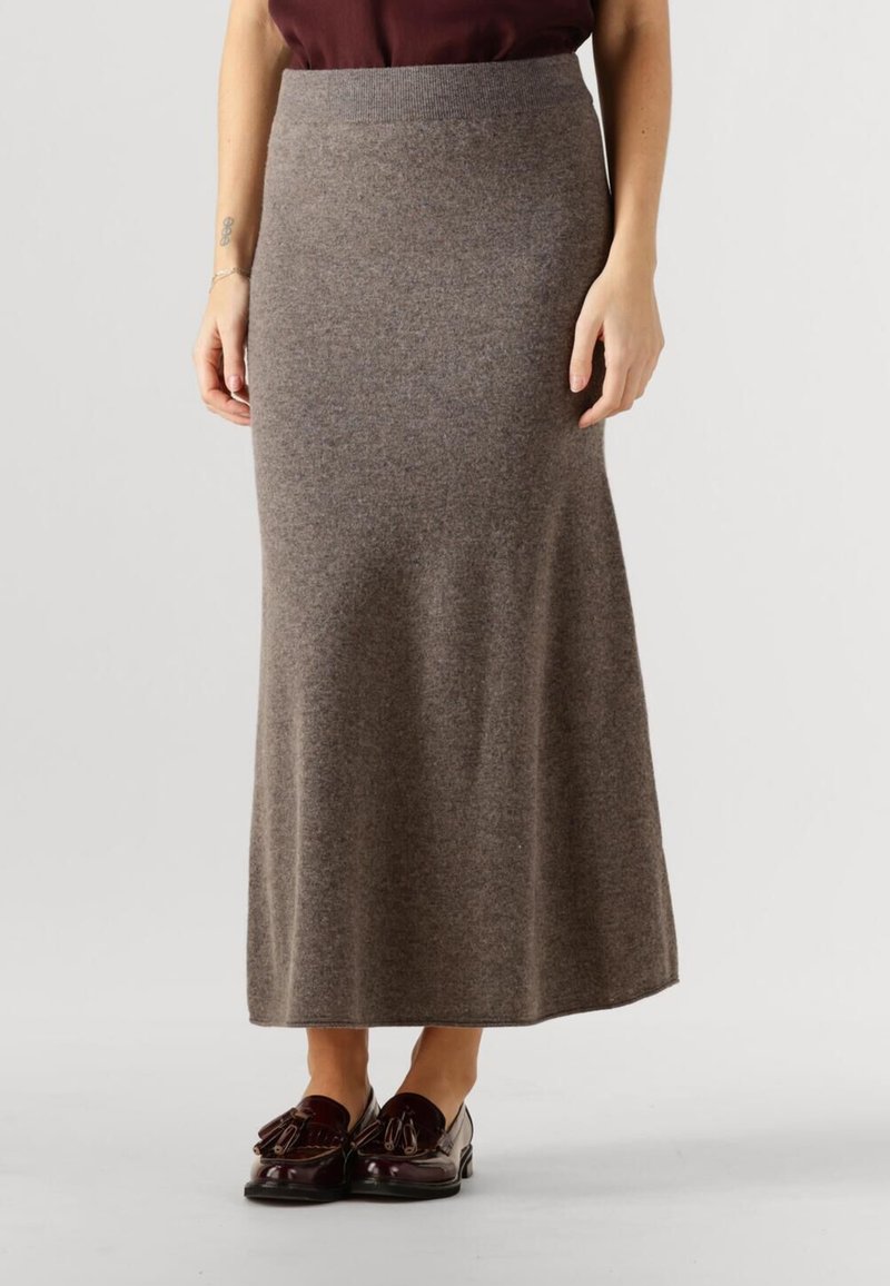 Long, brown knit skirt with a fitted waistband. Soft texture with a smooth finish, paired with dark loafers featuring decorative accents.