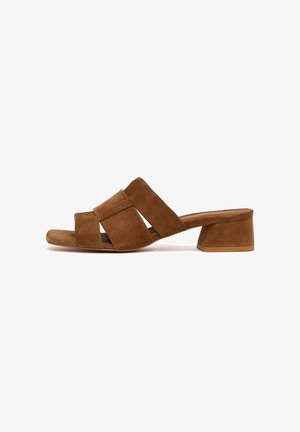 Sandalo mule in camoscio marrone con punta aperta, cinturini larghi incrociati e tacco basso a blocco su sfondo bianco.