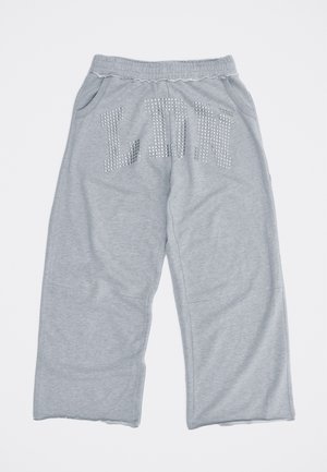 Pantalon de survêtement gris clair à jambes larges avec taille élastique, poches latérales, et lettres cloutées "LDN" sur le devant.