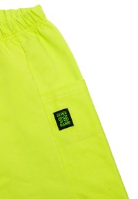 Neon żółte szorty z elastycznym pasem, z boczną kieszenią i czarną metką "ZONE 95 GAME" wyszytą na kieszeni.