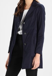 Marineblå, letvægts, skræddersyet trench coat med en notched krave, tre knapper og sidelommer, lavet af et glat stof.