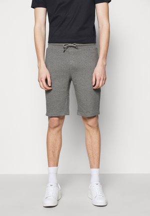 Shorts en coton gris mélangé avec une taille élastique et un cordon de serrage. Présentent une coupe droite et des détails de couture subtils. Portés avec des baskets blanches.