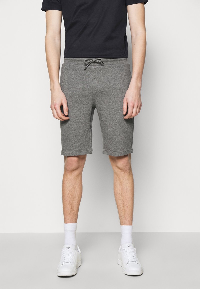 Šedé šortky z bavlněné směsi s elastickým pasem a šňůrkou na stažení. Vyznačují se rovnými nohavicemi a jemnými švy. Nosit s bílými teniskami.