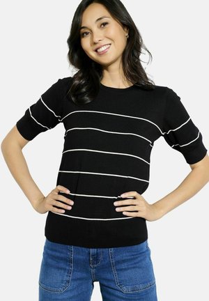 Pull en maille noir avec des rayures blanches horizontales, manches courtes, col rond et design ajusté. Porté avec un jean bleu.